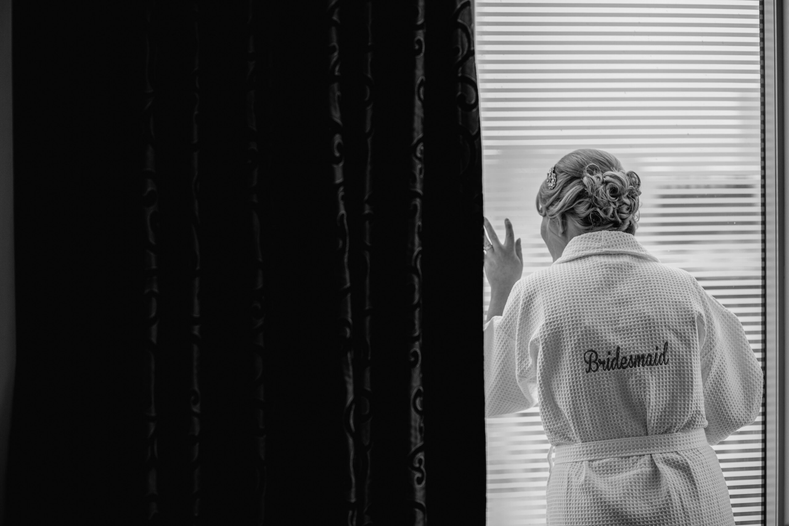 bridesmaid looking out window in a spa robe